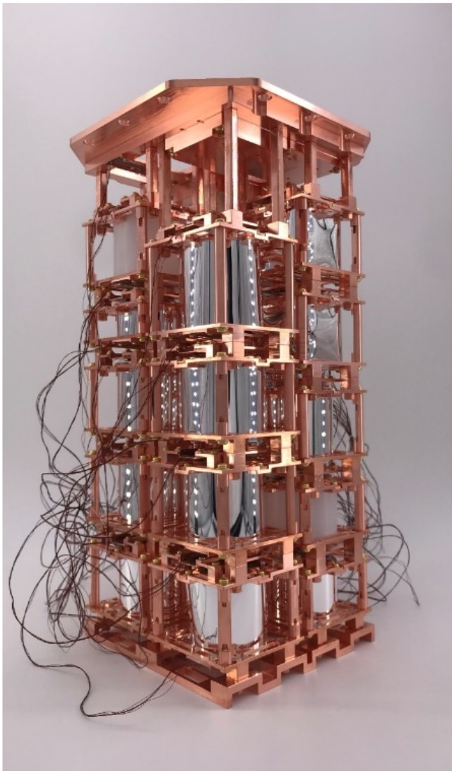The AMoRE-II detector tower containing multiple layers of stacked Li2MoO4 crystals, totaling 180 kg. Cylindrical silver-colored crystals are tightly integrated into a precise copper structure to determine the neutrino mass.
