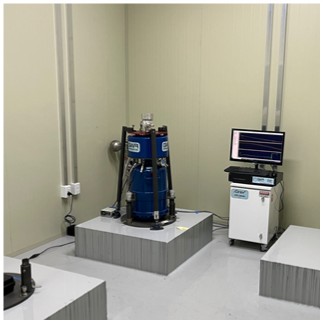A photograph of a gravity observation instrument installed on a raised platform next to a monitoring computer system in the YeMiGO laboratory.