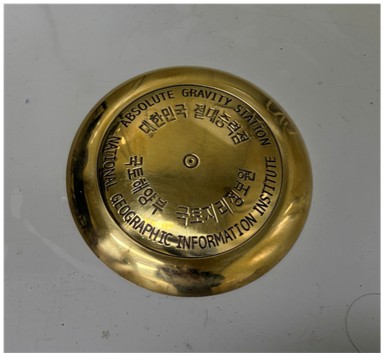 A close-up of the circular brass floor marker for the National Absolute Gravity Standard Station, established by the National Geographic Information Institute (NGII) on April 3, 2026.