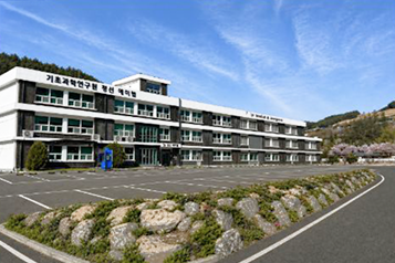 넓은 주차장 뒤로 기초과학연구원 건물이 보이는 전경입니다.